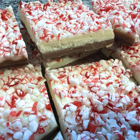 Close-up of peppermint bark with red and white candy pieces on a wooden surface.