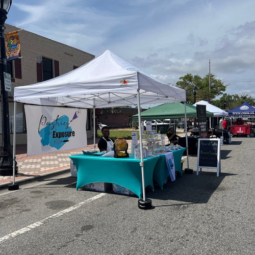 Outdoor event with a white tent and blue tablecloth, featuring a logo on the wall.