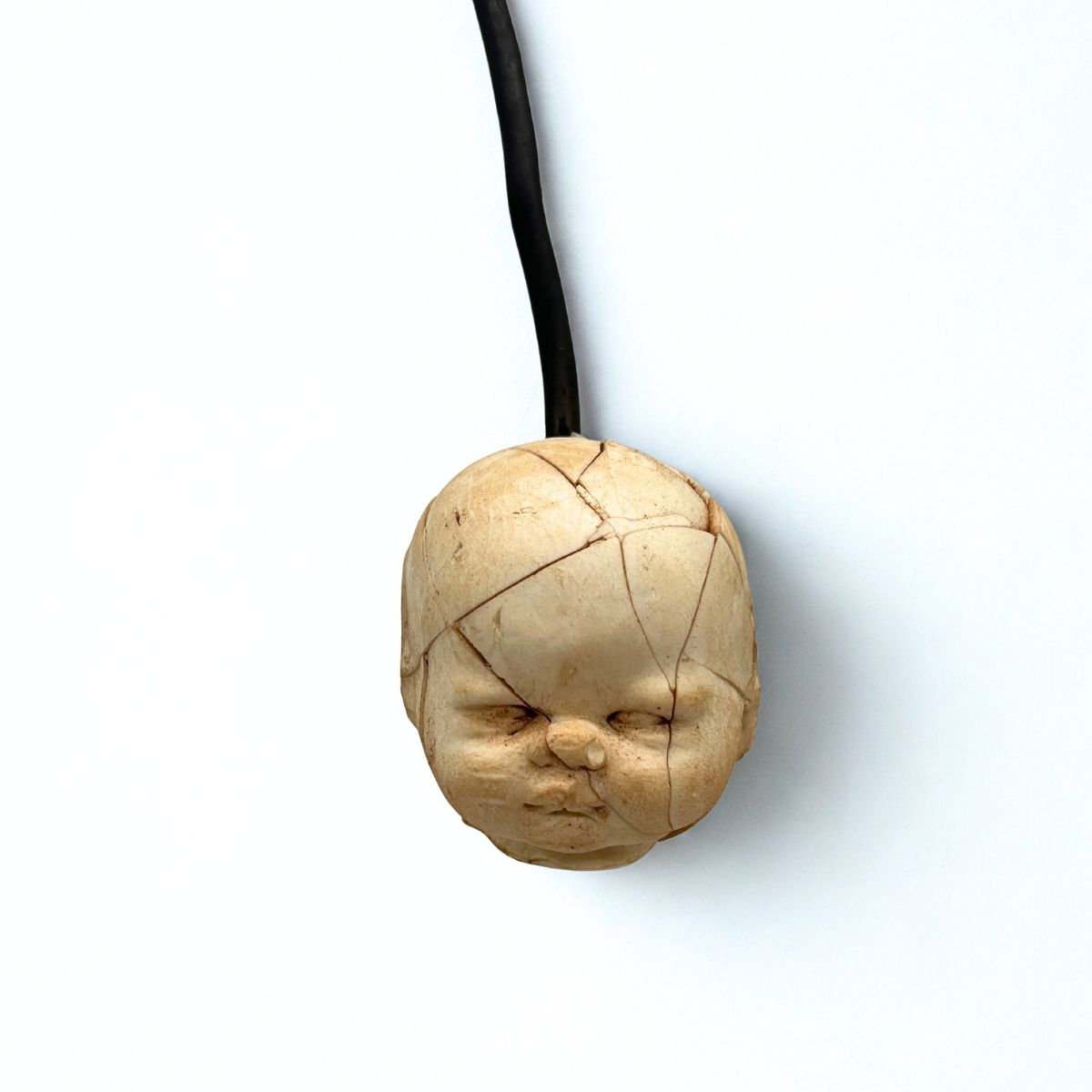 Wooden pendant shaped like a face on a white background