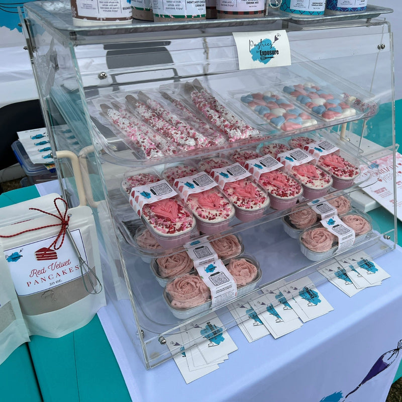 Display case with pink treats on a table with a blue background