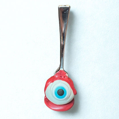 Spoon with a red eye-shaped handle on a white background