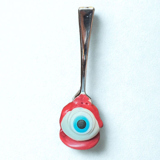 Spoon with a red eye-shaped handle on a white background