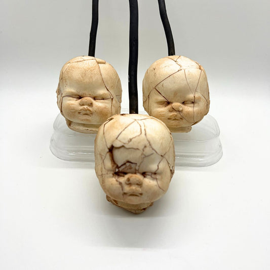 Three stone carvings of faces on a white background