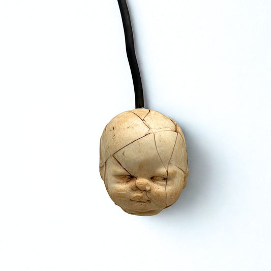 Wooden pendant shaped like a face on a white background