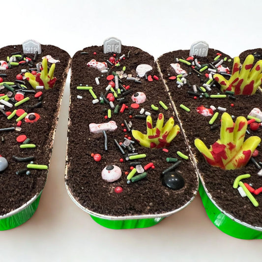 Three dessert cups decorated to look like a graveyard with cookies, candies, and icing.