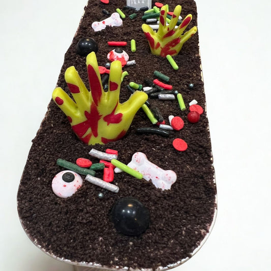 Decorative cake with zombie hand and skeleton hand designs on a white background