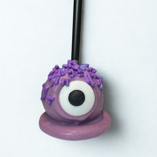 Purple candy with a single eye on a stick against a white background