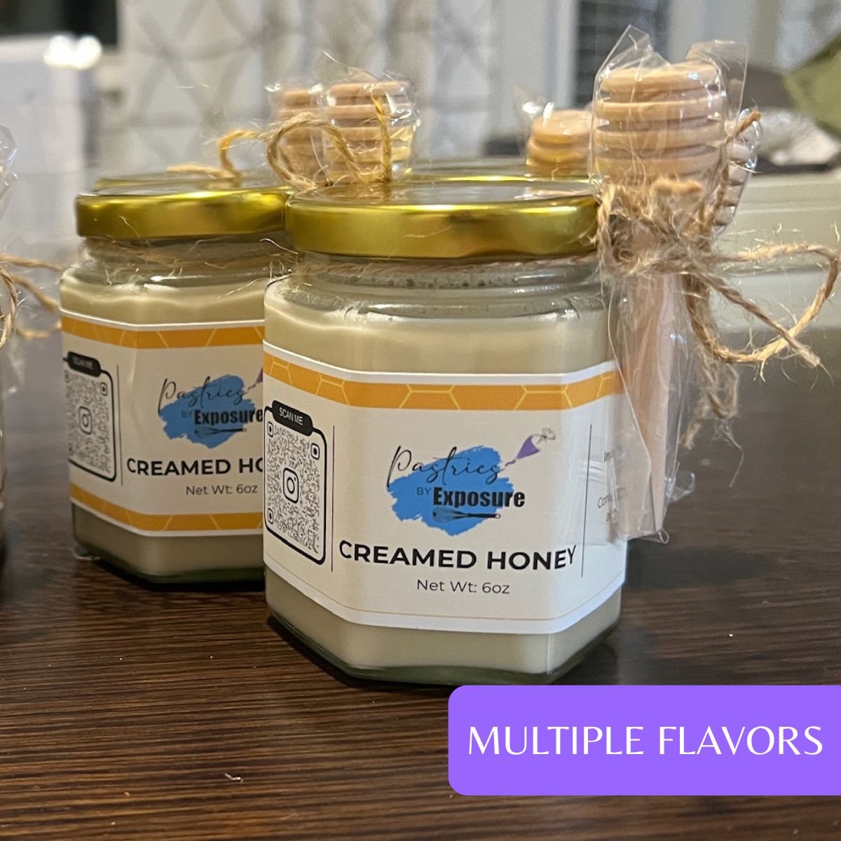 Jars of 'Creamed Honey' with visible branding on a wooden surface.